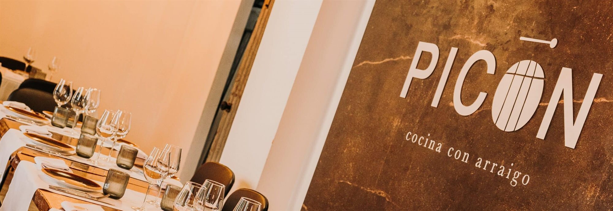 Sala principal de Picón, con mesas vestidas de blanco y el logotipo en la pared